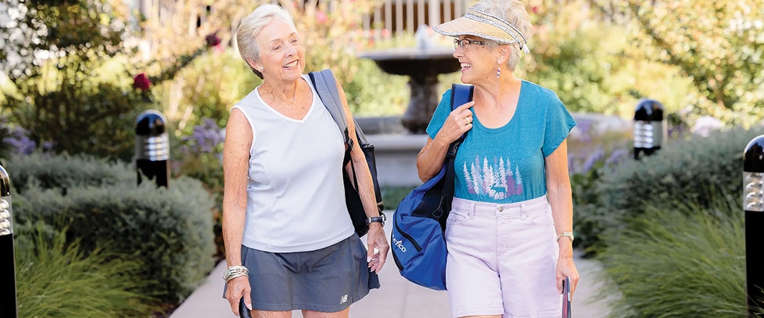 Two ladies walking together with pickleball bags Two ladies walking together with pickleball bags