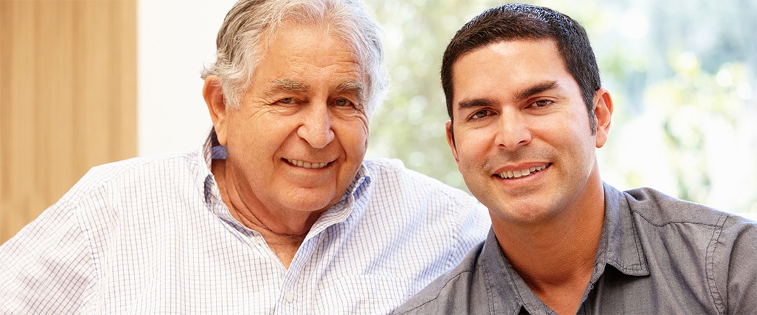 A son and father smiling together in a room. A son and father smiling together in a room.