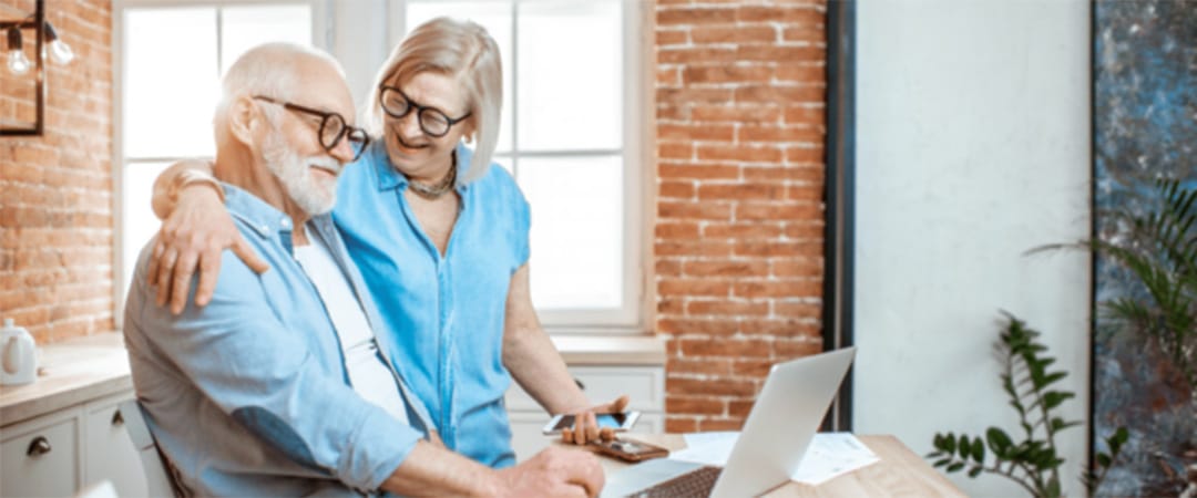 yolo-1080x450-192 An elderly woman with her arm around an elderly man while looking at a computer