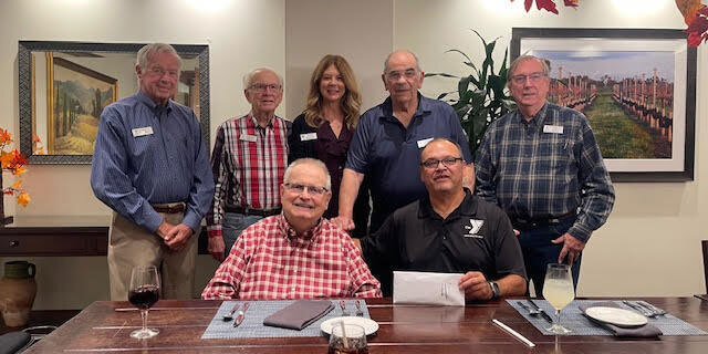 Five residents, a representative of the Armed Services YMCA and a staff member are posing as they present a donation check highlighting their service.